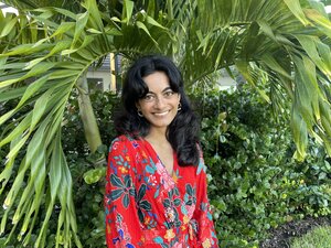 A photo of Shivani. She is smiling at the camera, has long, dark hair, and is wearing a red shirt.