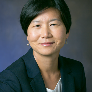 A photo of Dr. Soo Ah Kwon. She is smiling at the camera. Her hair is short, and she wears a dark suit.